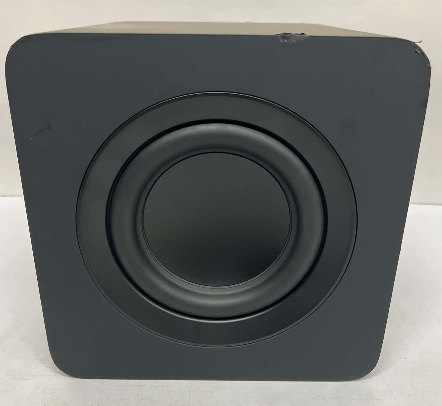 Close-up view of a black wireless subwoofer with a circular speaker grill.