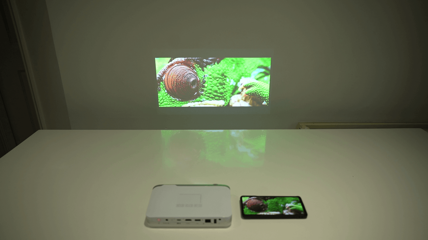 Pico Genie M550 Plus 4.0 Smart Projector projecting an image of a snail next to a smartphone.