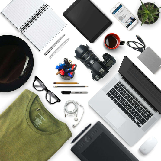 Flat lay of creative workspace with a laptop, camera, notebook, tablet, and stationary items for productivity.
