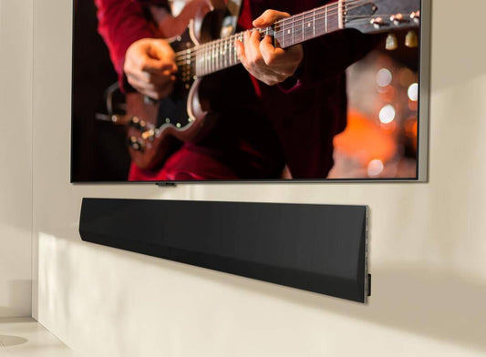 LG soundbar mounted below a TV displaying a musician playing guitar, enhancing home audio experience.