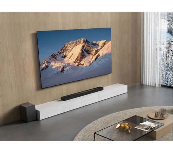 TCL Q65H 5.1 WIRELESS 580W HOME CINEMA SOUNDBAR SUBWOOFER DOLBY ATMOS Q65HK placed below a TV in a modern living room.
