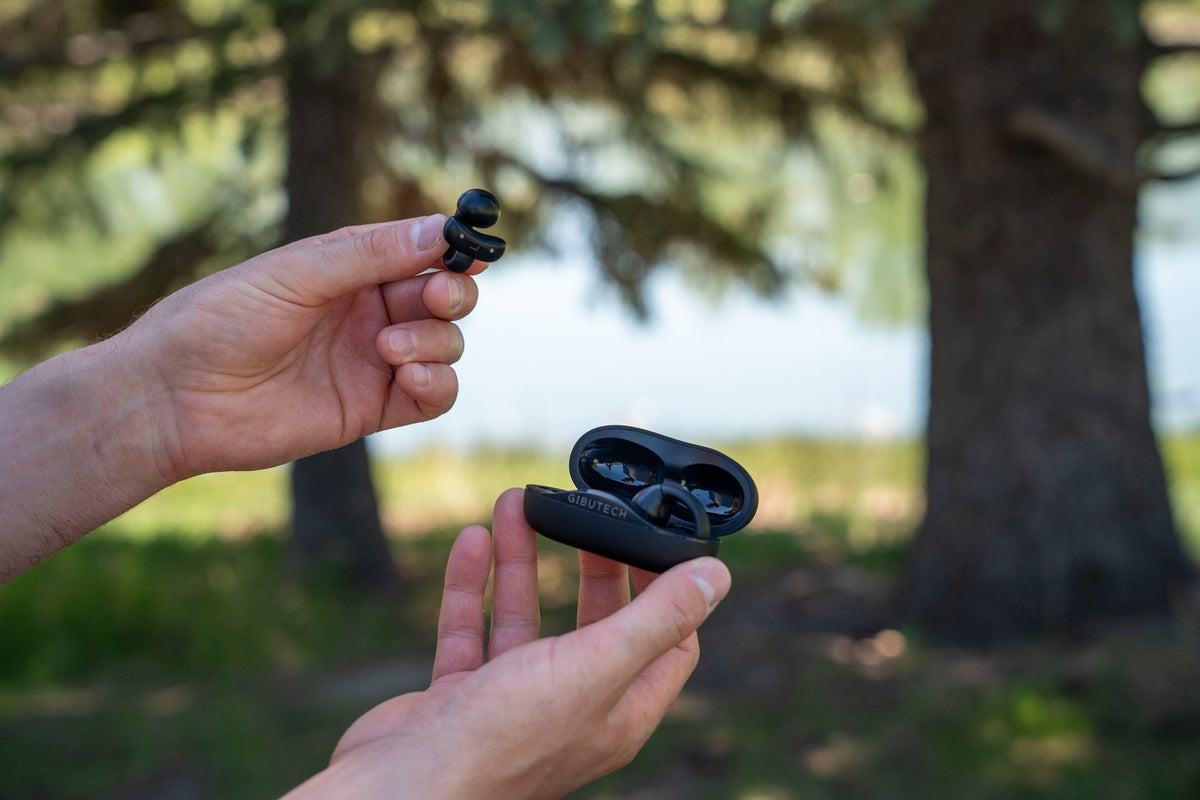 Gibutech Ultra Open Wireless bone conduction earbuds with dual mic held in hand outdoors.