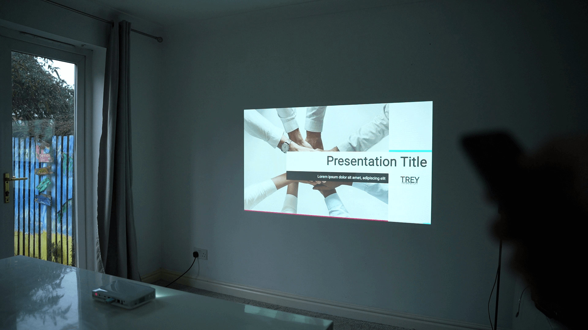 Image of a Pico Genie M550 Plus 4.0 Smart Projector displaying a presentation on a wall.