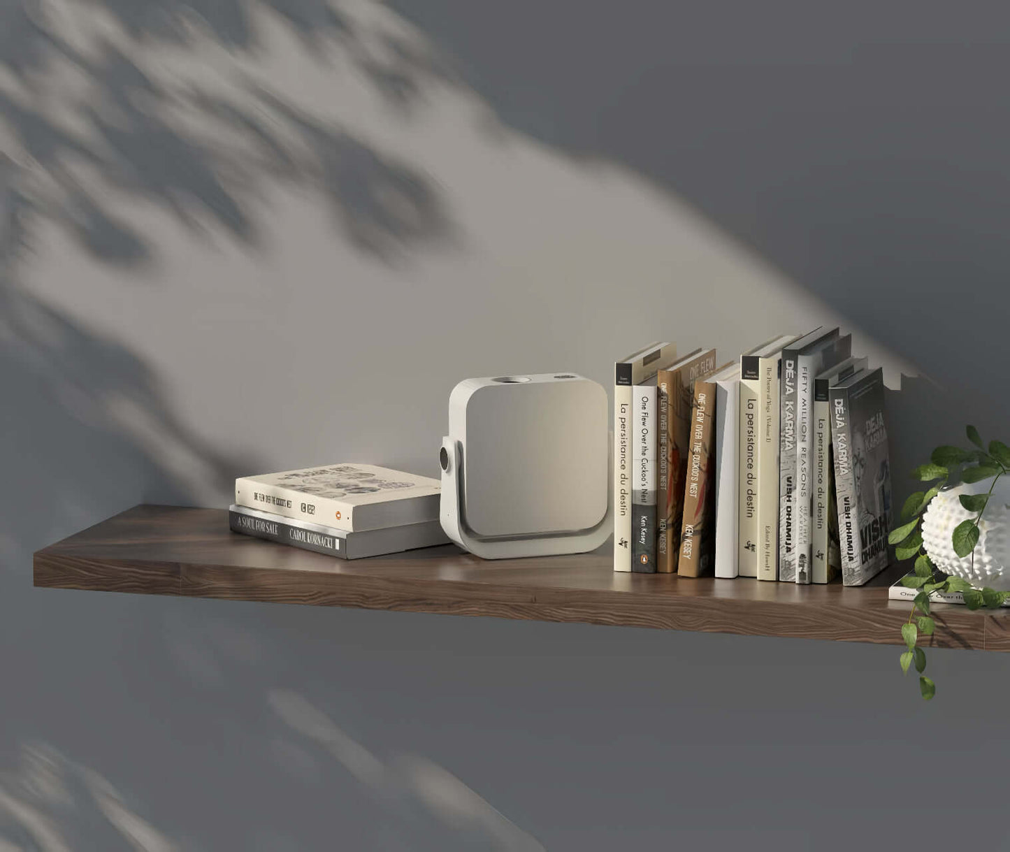 Pico Genie L300 LED 1080p Smart Projector on a wooden shelf with books and a plant.